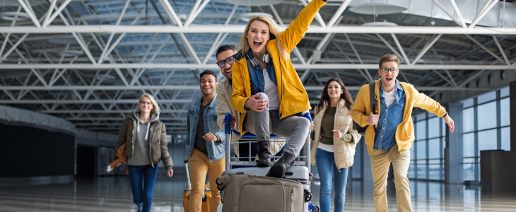 A family riding on suitcases through an airport